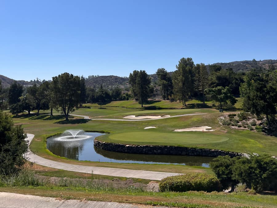 A putting green beside a pond and fountain